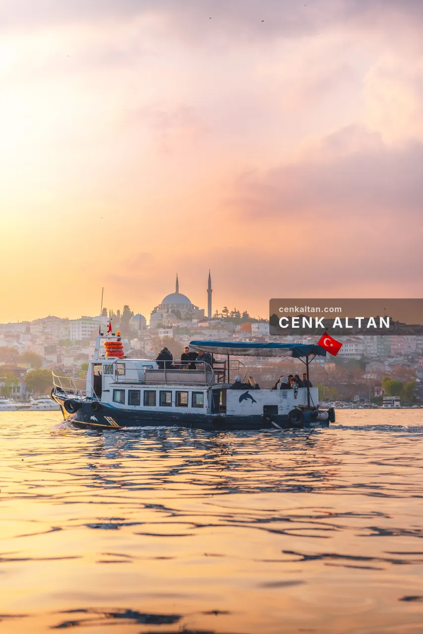 Pembe turuncu gün batımında Haliç’te tekne ve Süleymaniye silüeti
