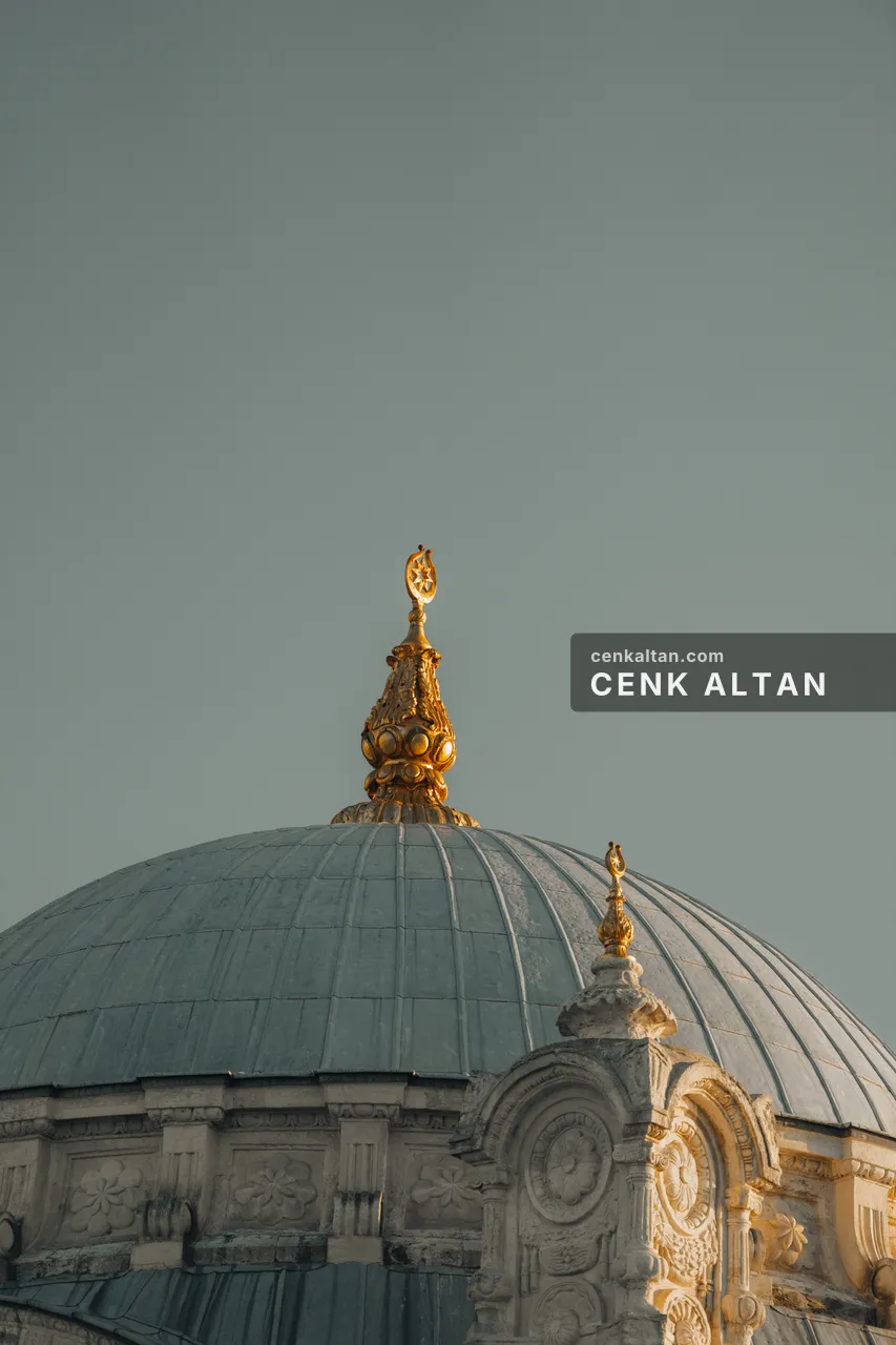 Gri gökte Ortaköy Camii'nin kubbesi ve altın alemi; kubbe kurşunu mavi-gri, süslemeler sabah ışığında