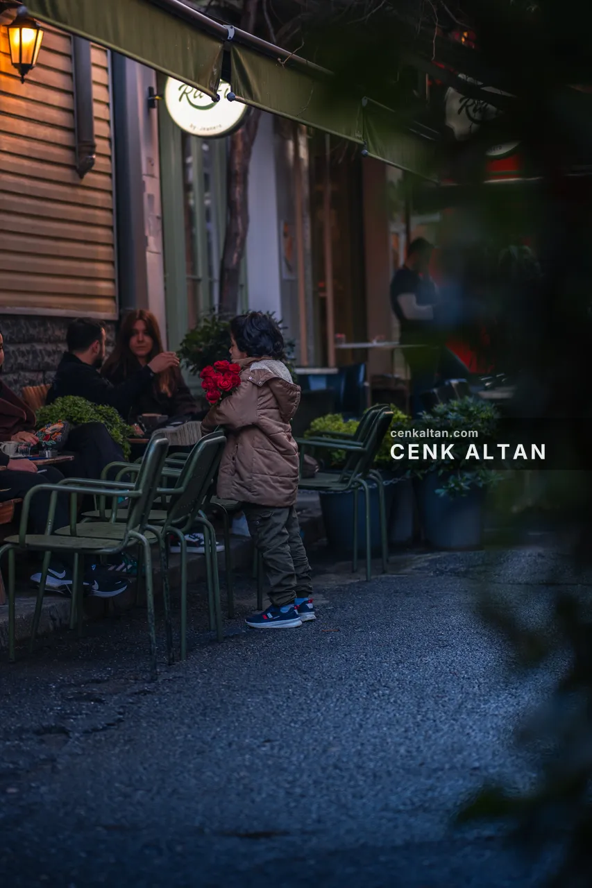 Akşam bir kafenin dışında oturan insanlar, sıcak lamba ışığı