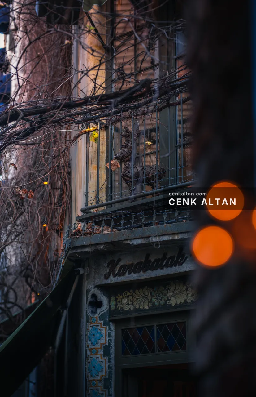 Eski bir binanın cephesi, tabela ve önde bulanık sıcak ışıklar