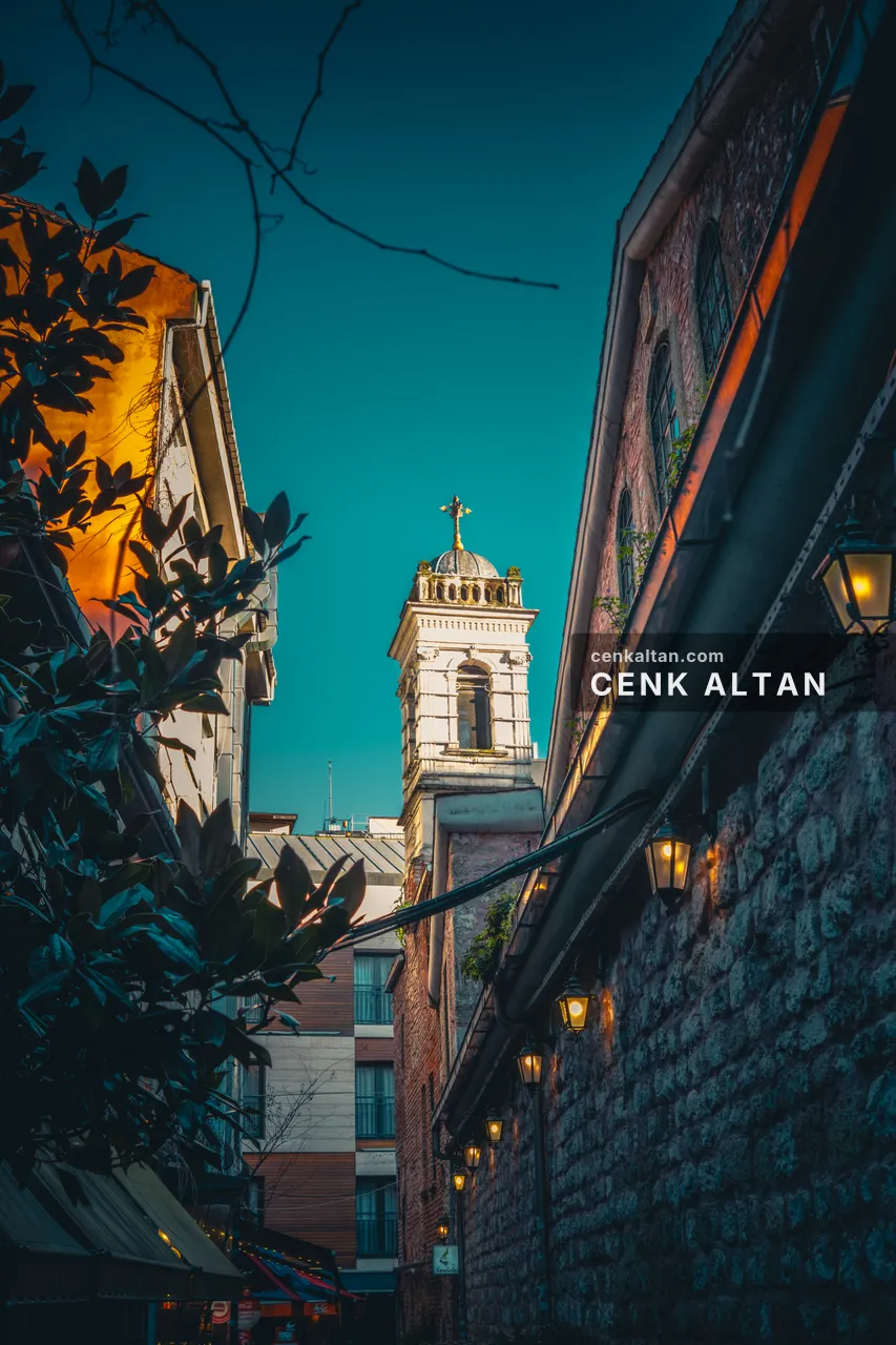 Dar bir sokaktan bakınca akşam gökyüzünde kilise kulesi