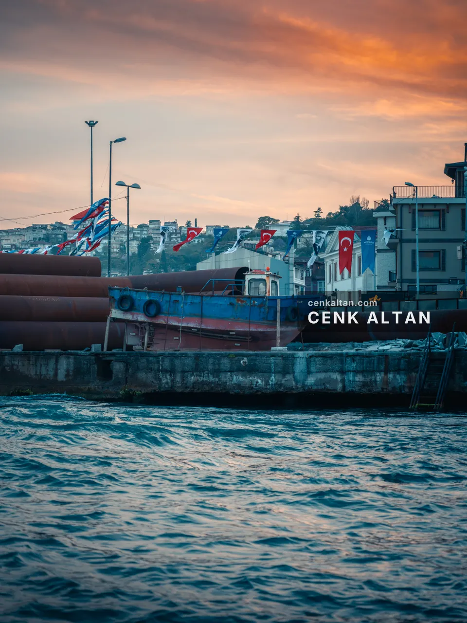 Dalgalı denizden bakışla bayraklı bir rıhtım ve tekneler