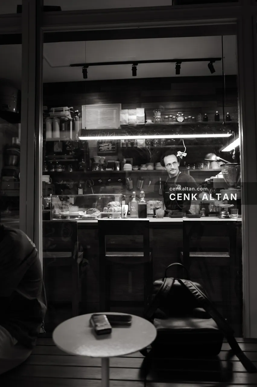 Siyah beyaz: cam arkasında barista ve önde bir tabure