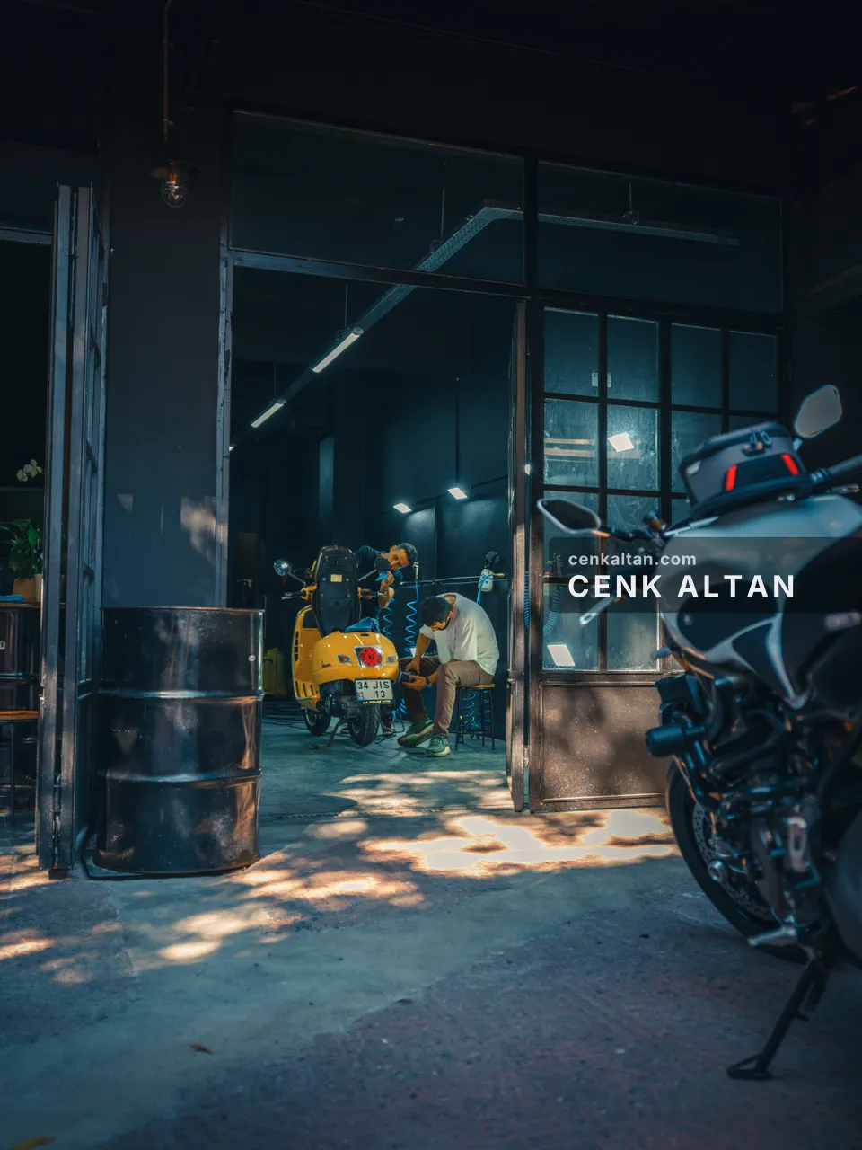 Loş bir atölyede motosikletler ve kapıdan giren ışık