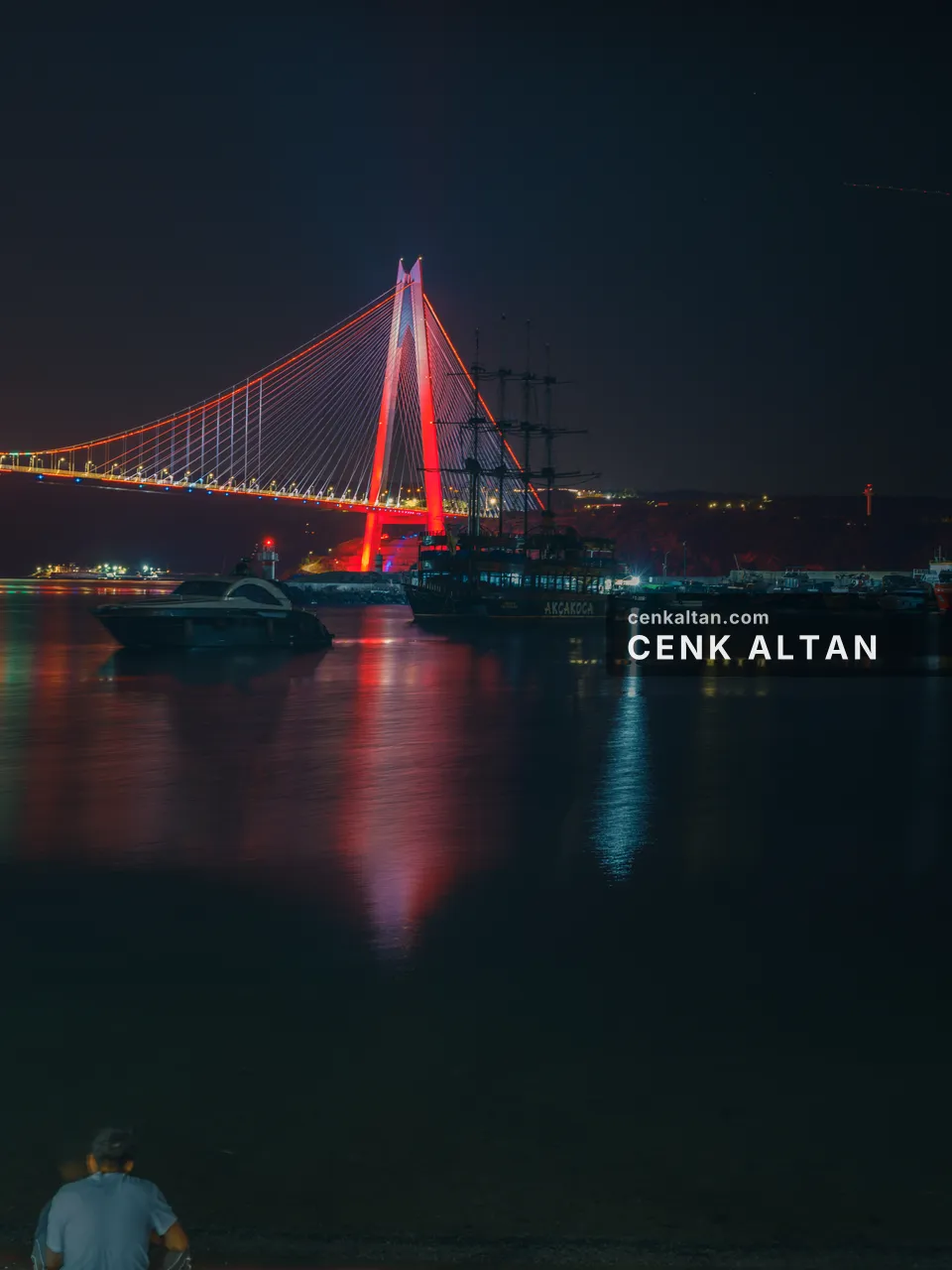 Kırmızı aydınlatmalı köprü ve önünde geçen gemi, gece