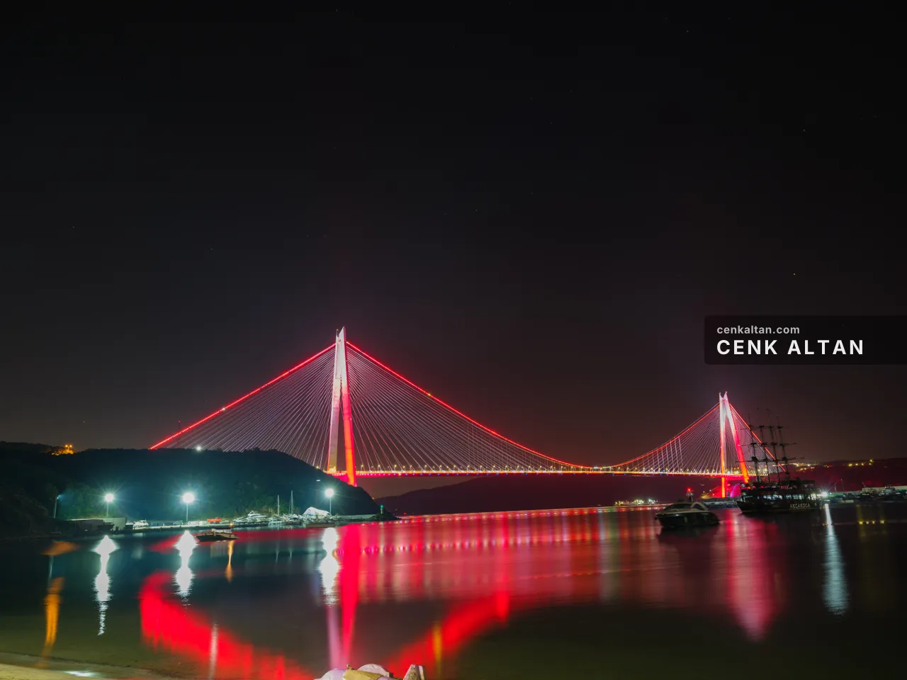 Gece kırmızı ışıklı köprünün geniş görünümü ve suda uzun yansımalar