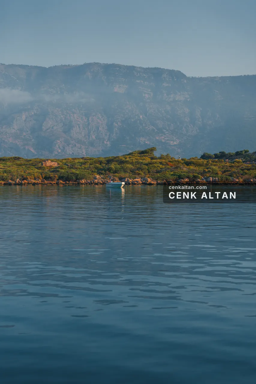 Sisli dağların önünde sakin deniz ve tek tekne